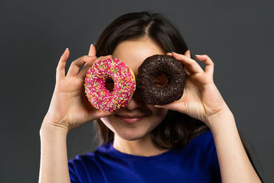 Portrait of girl holding ice cream against black background