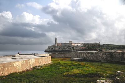 View of castle by sea against cloudy sky