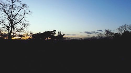 Silhouette trees on landscape against clear sky