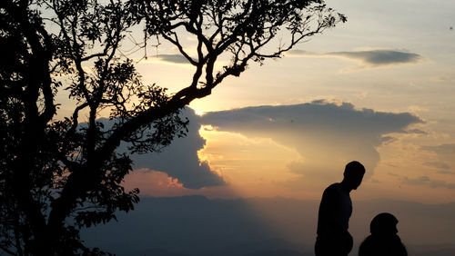 Silhouette people by tree against sky during sunset