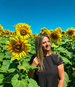 Portrait of smiling woman with sunflower against plants