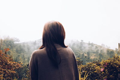 Rear view of woman on mountain in foggy weather
