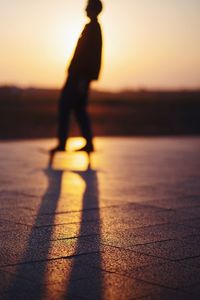 Silhouette person standing on beach during sunset