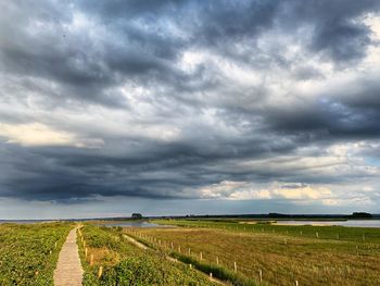 Scenic view of field against cloudy sky