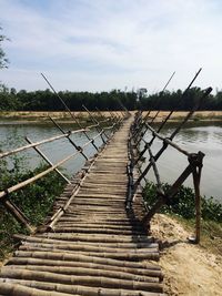 Wooden pier over river against sky