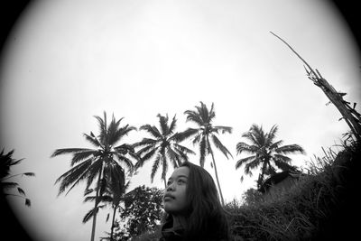 Young woman with palm tree against sky