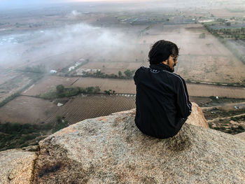 Rear view of woman sitting on land