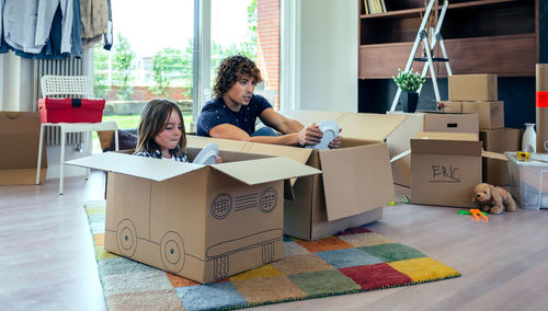 Father and son with plates sitting in cardboard boxes at home