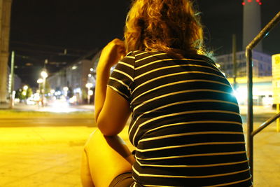 Rear view of woman standing in illuminated city at night