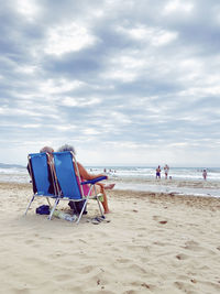 Deck chairs on beach against sky