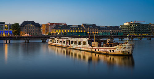 Bridge over river against buildings in city against clear sky