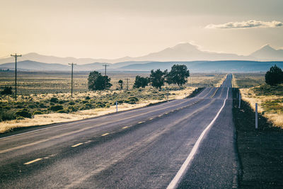 Long straight highway with telegraph lines leading to distant mountains in oregon