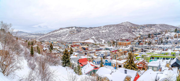 Aerial view of townscape by snow covered mountain against sky