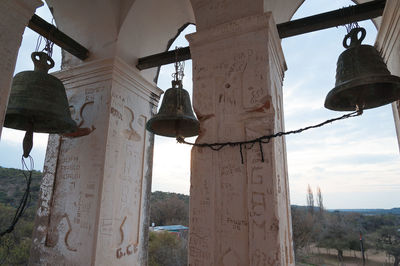 Low angle view of bell hanging outside building against sky