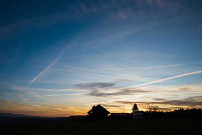 Silhouette houses against sky during sunset