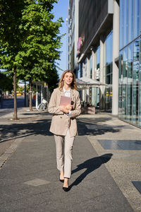 Portrait of young woman standing in city