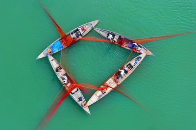 Fishermen draw their boats together so they can help each other lower a large net into the water. 
