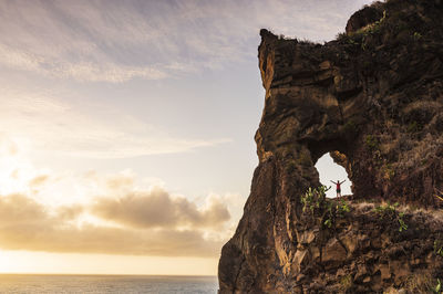 Rock formation by sea against sky during sunset