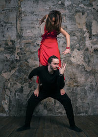 Full length of man and woman dancing on floor against wall