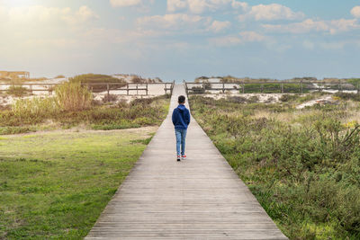 Rear view of man walking on footbridge