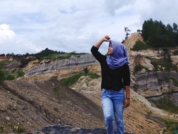 Young woman wearing hijab standing on mountain against sky