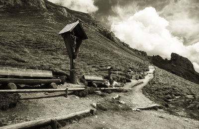 Cross on wooden structure by walkway at mountain