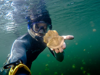 Portrait of scuba diver holding jellyfish in sea