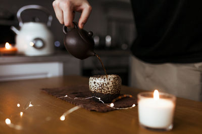 Young man pouring chinese tea from a teapot into a chinese cup in his modern kitchen