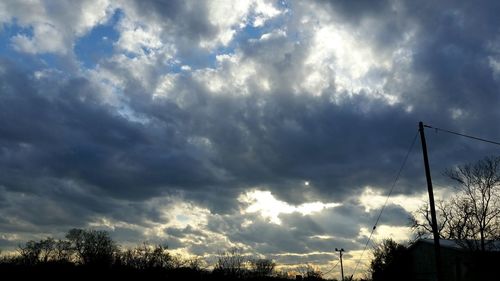 Silhouette of trees against cloudy sky