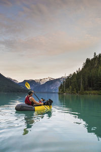 Father paddling with son on scenic lake, canada.