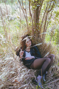 Full length of young woman sitting at forest