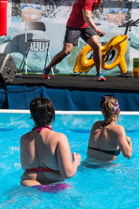 Rear view of women wearing bikini swimming in pool
