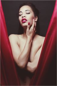 Young naked woman in between red drapes