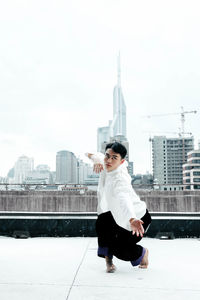 Full length of woman standing by buildings against sky in city