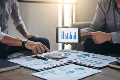 Midsection of colleagues working over graph in office