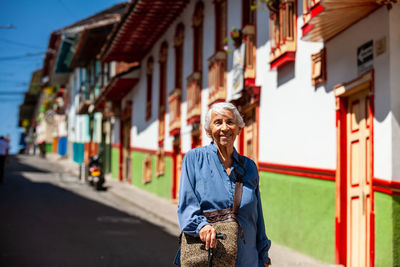 Side view of young woman standing on street in city