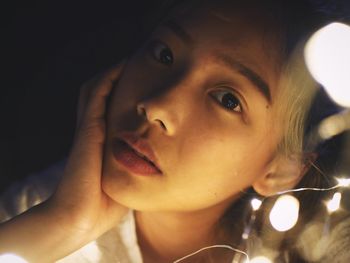 Close-up portrait of young woman with string lights