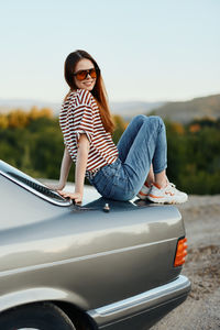 Young woman sitting on car