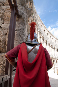 Rear view of woman standing by building against sky