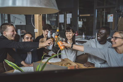 Smiling coworkers toasting beer at workplace