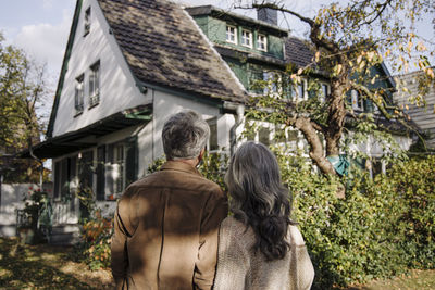 Rear view of senior couple in garden of their home in autumn