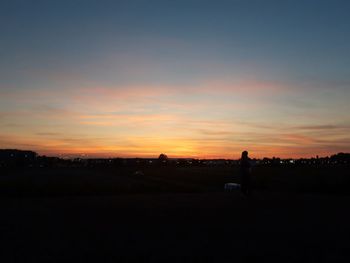 Silhouette trees on field against sky during sunset