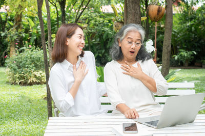 Smiling young woman using phone while sitting on table