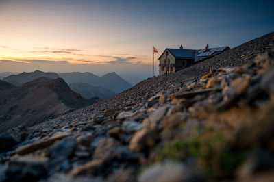 Surface level of land against house and sky during sunset