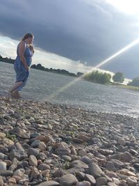 Woman on rocks at beach against sky