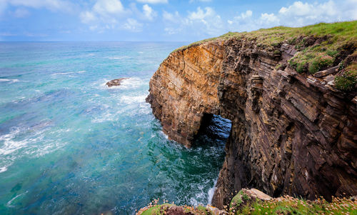 Rock formation in sea against sky