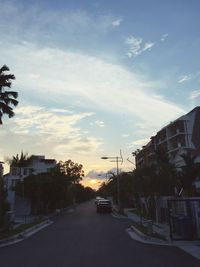 Cars on road against cloudy sky