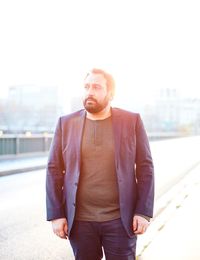 Man wearing blazer on street against sky