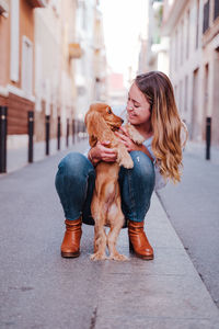 Woman with dog on footpath in city