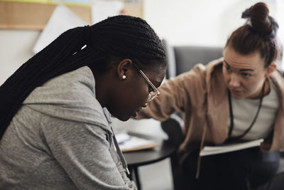 Mental health professional consoling sad female student in school office